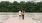 a man and woman walking on a dock by water