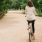 a man riding a bicycle on a path surrounded by trees